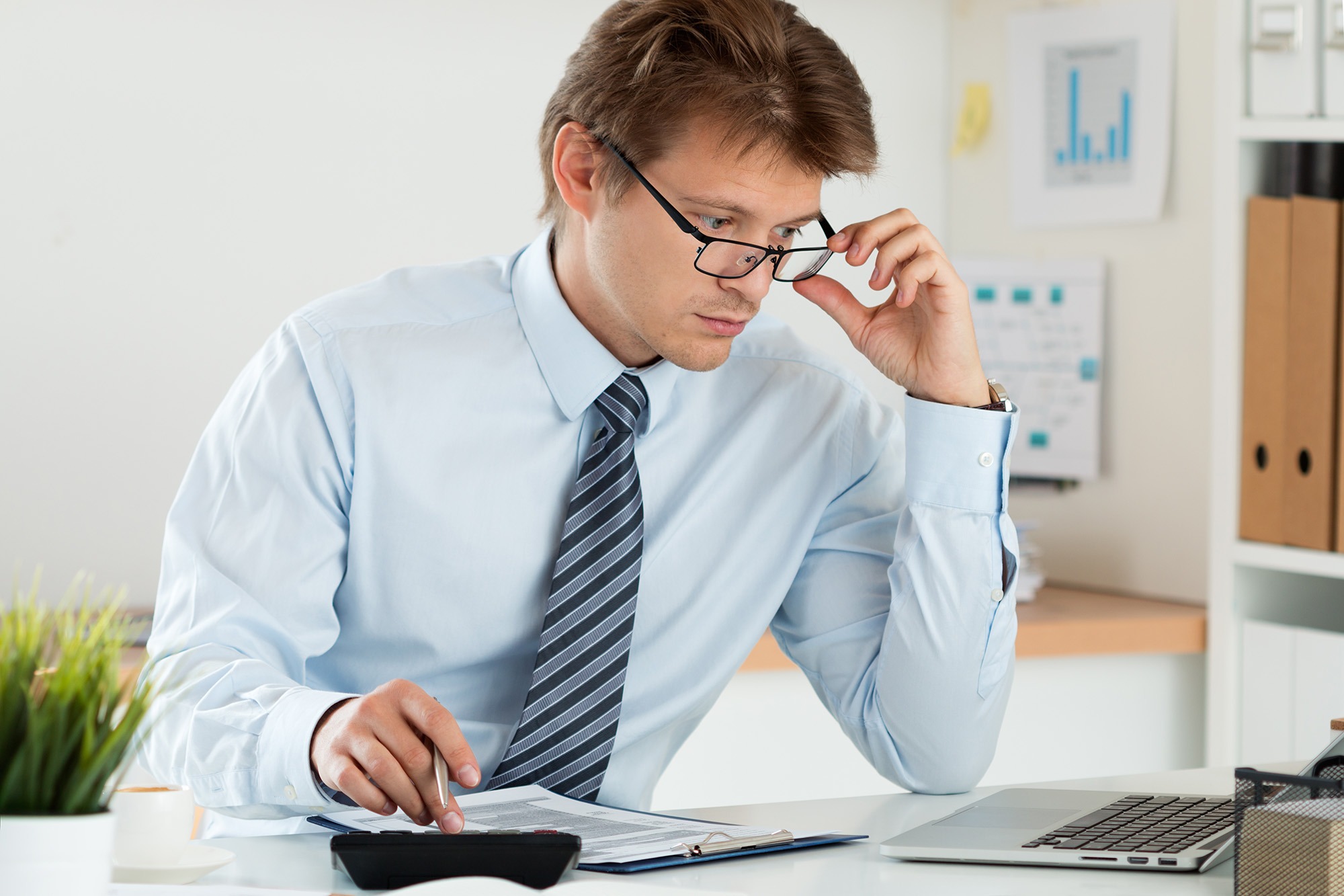 Portrait of bookkeeper or financial inspector adjusting his glasses